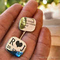 Personalized square silver cufflinks with engraved lettering, shown in a hand.